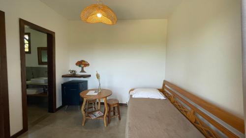 a bedroom with a bed and a table with a chair at Pousada Sete Quedas in Carrancas