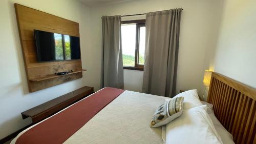 a bedroom with a bed with a television and a window at Pousada Sete Quedas in Carrancas