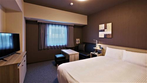 una camera d'albergo con letto e TV di Hotel Route Inn Imabari a Imabari