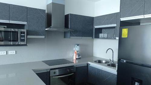 a kitchen with gray cabinets and a sink at Grand Diamond Beach Tonsupa in Tonsupa