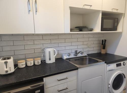 um balcão de cozinha com um lavatório e um micro-ondas em Guest House on Guthrie em Havelock North