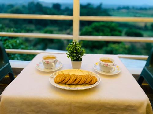 a table with a plate of food and two cups of tea at Rabbit Hill Farm in Bangalore