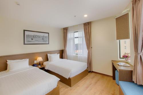 a hotel room with two beds and a window at Central Hotel & Spa Danang in Da Nang