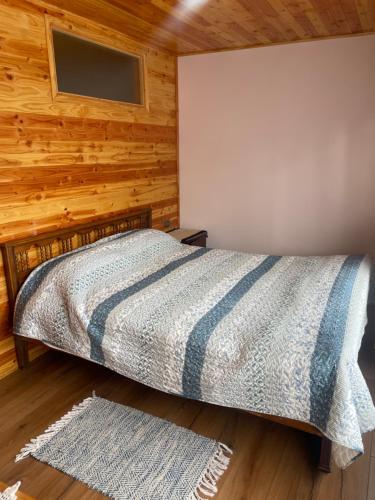 sypialnia z łóżkiem w drewnianej ścianie w obiekcie Cabaña 300 mts. del centro w mieście Licán Ray
