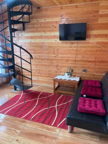 ein Wohnzimmer mit einem Sofa und einem TV an der Wand in der Unterkunft Cabaña 300 mts. del centro in Licán Ray