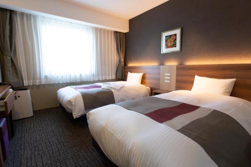 a hotel room with two beds and a window at Shinsaibashi Grand Hotel Osaka in Osaka