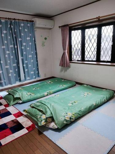 two beds in a room with two windows at Home Stay 北国分 in Ichikawa