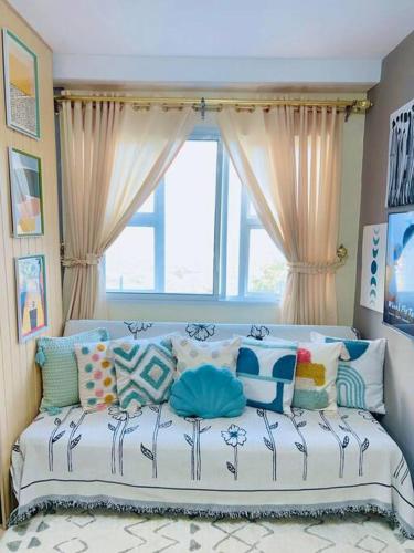 ein Zimmer mit einem Sofa mit Kissen und einem Fenster in der Unterkunft Pineview Haven in Baguio in Baguio City