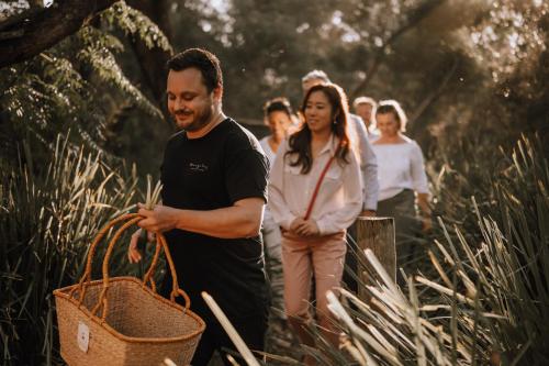 a group of people walking through the woods with a basket at Bangalay Luxury Villas in Shoalhaven Heads
