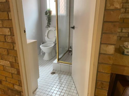 uma casa de banho com um WC e uma cabina de duche em vidro. em Spacious studio unit em Rochedale South