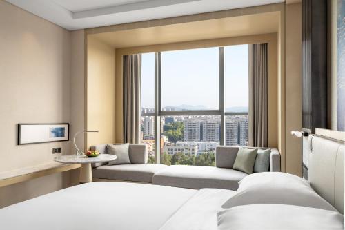 a hotel room with a bed and a large window at Courtyard by Marriott Shanwei Haifeng in Shanwei