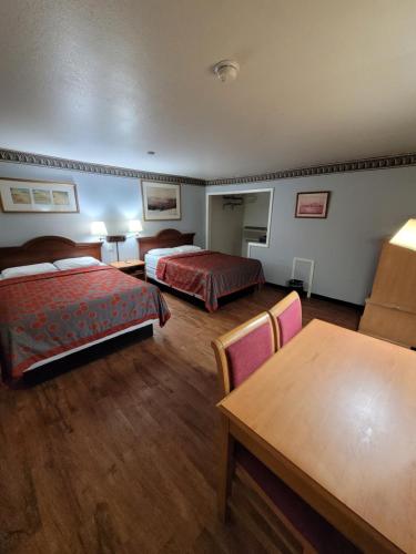 una camera d'albergo con due letti e un tavolo di Sands Motel a Portales