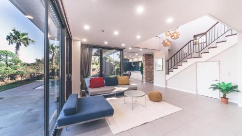 a living room with a blue couch and a staircase at Jeju Private unit for family or group in Jeju