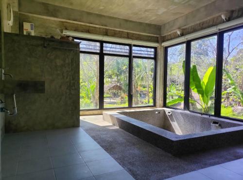 a large bath tub in a room with windows at Century Hotspring Resort in Phra Chedi Sam Ong