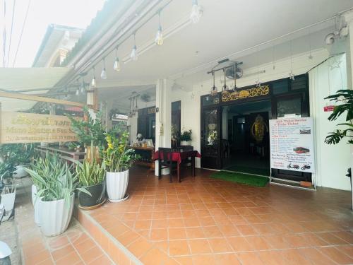 a restaurant with tables and potted plants in a building at Mano boutique sun shine in Luang Prabang