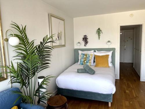 - une chambre avec un lit doté d'oreillers et d'une plante dans l'établissement Tour Eiffel - Studio vue imprenable au-dessus des toits, balcon, à Paris