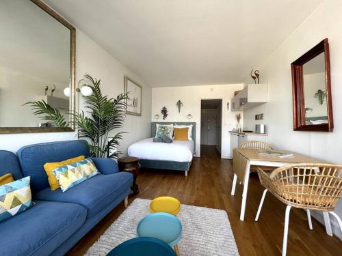 un salon avec un canapé bleu et une chambre dans l'établissement Tour Eiffel - Studio vue imprenable au-dessus des toits, balcon, à Paris