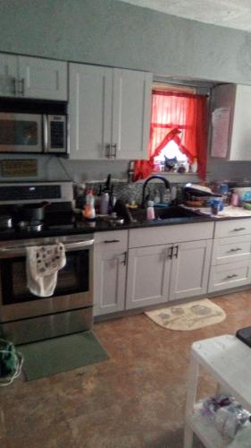 a kitchen with white cabinets and a stove top oven at Peaceful Mountain Home in West Homestead