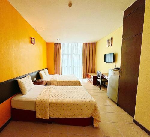 una camera d'albergo con due letti e una televisione di GRAND FAR EAST HOTEL SDN BHD a Masai
