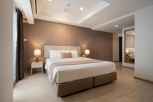 1 dormitorio con 1 cama grande y 2 lámparas en Aspira Residence Ruamrudee, en Bangkok