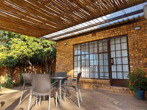 a patio with a table and chairs under a wooden pergola at Wapadrand Guest Suite in Pretoria
