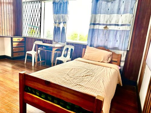 a bedroom with a bed and a table and a window at Baguio BELL Staycation in Baguio