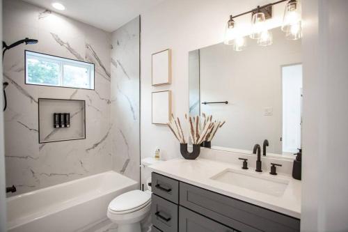 a bathroom with a sink and a toilet and a mirror at Stylish 3 Story Townhouse near East Downtown in Houston