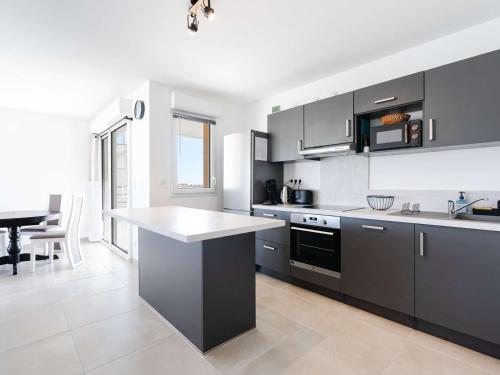 une cuisine avec des armoires en noir et blanc et une table dans l'établissement Appartement T3 Climatisé avec WIFI, Balcon et Parking à 300m de la Plage - Narbonne Plage - FR-1-409-255, à Narbonne