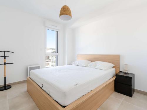une chambre avec un lit avec des draps blancs et une fenêtre dans l'établissement Appartement T3 Climatisé avec WIFI, Balcon et Parking à 300m de la Plage - Narbonne Plage - FR-1-409-255, à Narbonne