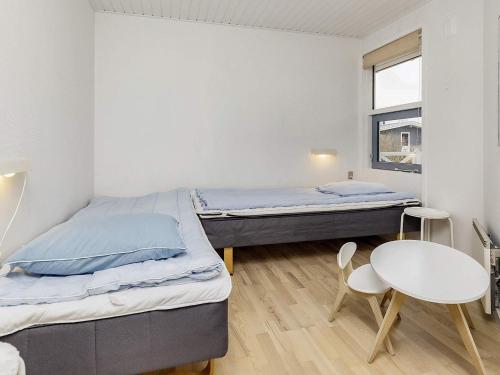 two beds in a room with a table and chairs at Four-Bedroom Holiday home in Væggerløse 22 in Marielyst