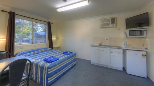 Habitación con cama y cocina con ventana en Barcaldine Caravan Park, en Barcaldine