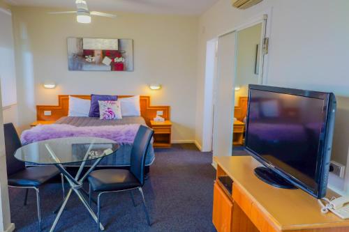 um quarto com uma cama, uma mesa e uma televisão em Abbotsleigh Motor Inn em Armidale