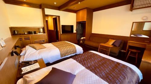 a hotel room with two beds and a couch at Ryokan Wakaba in Minamioguni