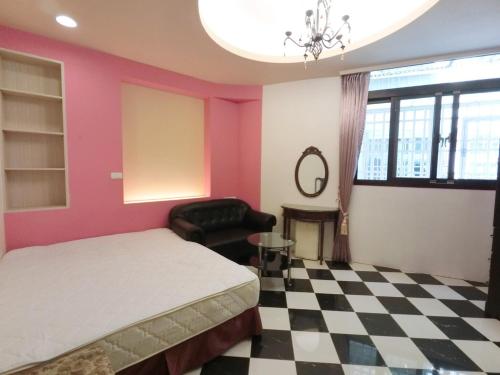 a bedroom with a bed and a chair and a checkered floor at Miss You House in Taichung