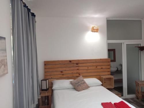 Schlafzimmer mit einem weißen Bett mit einem Kopfteil aus Holz in der Unterkunft El Puente in El Paredón Buena Vista