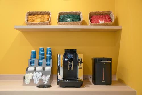 a coffee maker on a shelf with baskets at Hop Inn Tokyo Iidabashi in Tokyo