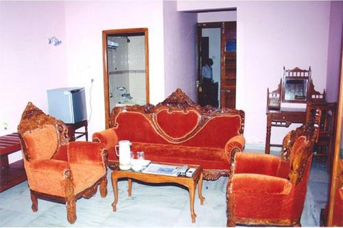 a living room with a couch and two chairs and a table at Hotel Soorya Inn in Puducherry