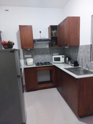 a kitchen with wooden cabinets and a sink and a refrigerator at Elixia Emerald 2 Bed Room Fully Furnished Apartment, Colombo, Malabe in Malabe