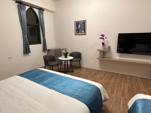 a bedroom with a bed and a table and a tv at Athens Vacation Club House in Magong