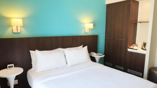 a bedroom with a large bed with a blue wall at Wyndham Garden i-City Shah Alam in Shah Alam