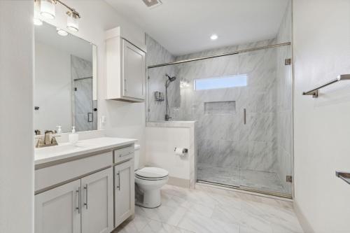 a white bathroom with a shower and a toilet at Large BackYard & Patio - Family Friendly - Near Downtown Dallas! in Dallas