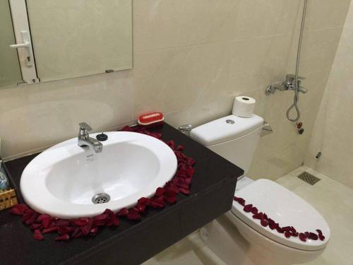 een badkamer met een wastafel en een toilet met rode bloemen bij Liên Mỹ Tâm Hotel PQ - by BAY LUXURY in Phu Quoc