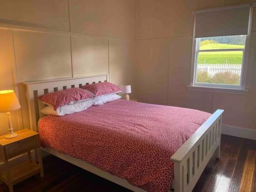 1 dormitorio con 1 cama con edredón rojo y ventana en Lola's Lilydale - entire house en Lilydale