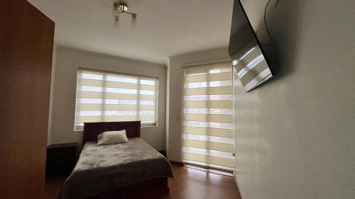 ein kleines Schlafzimmer mit einem Bett und zwei Fenstern in der Unterkunft Departamento moderno con gran espacio in Cuenca
