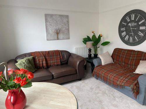 a living room with two couches and a clock at North Street Flat in Bristol
