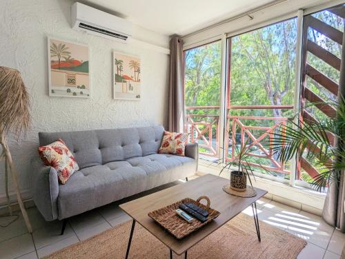 a living room with a couch and a large window at "Côté Lagon" à deux pas du lagon in Saint-Paul