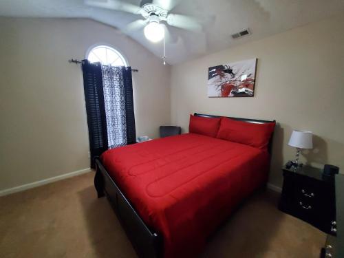 a bedroom with a red bed with a ceiling fan at Haven Away From Home Ideal For Long Term Stays in Fayetteville
