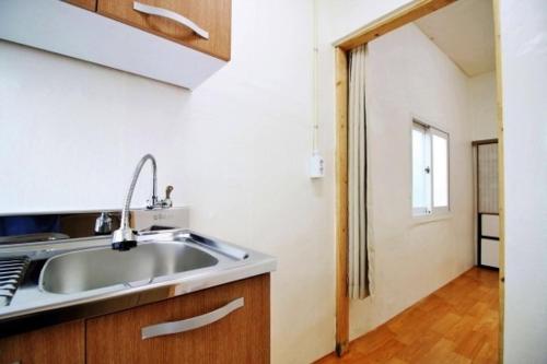 a kitchen with a sink and a door to a hallway at Dodam in Busan