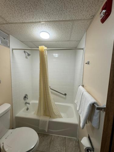 y baño con bañera, aseo y ducha. en Econo Lodge, en Waite Park