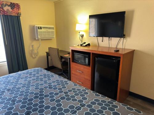 a hotel room with a bed and a flat screen tv at Econo Lodge in Waite Park
